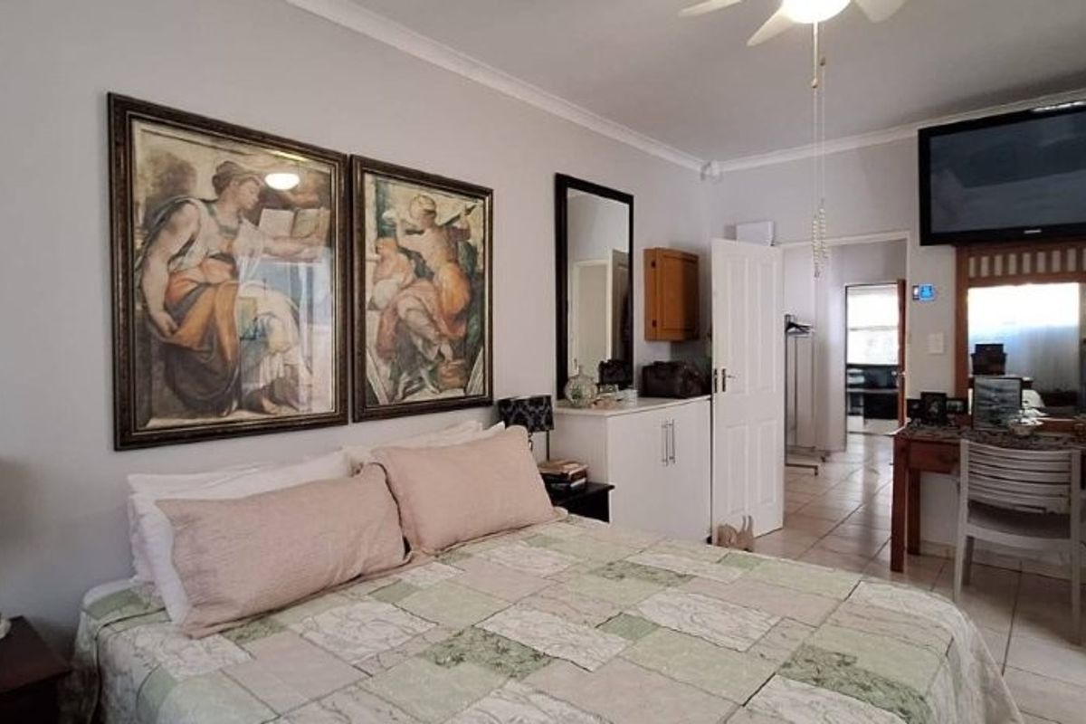 A functional bedroom featuring tiled flooring, a ceiling fan, and built-in storage, offering a comfortable and practical living space.
