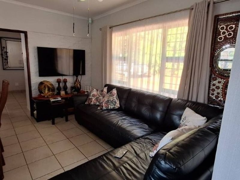 Open plan living and dining area featuring tiled flooring and a functional kitchen layout with built-in appliances.