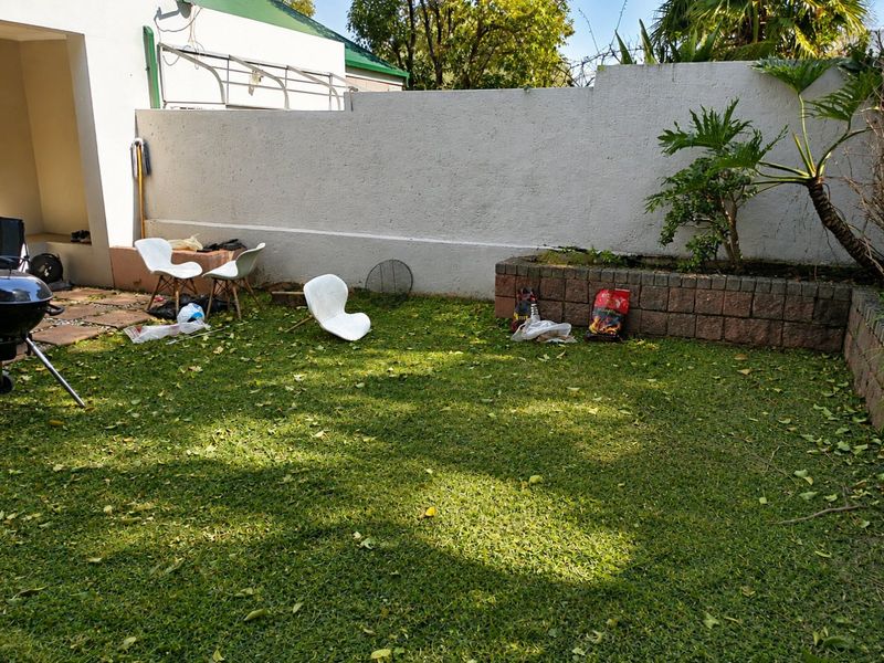 A private garden area featuring a brick planter box and perimeter wall, offering potential for landscaping and outdoor living improvements.