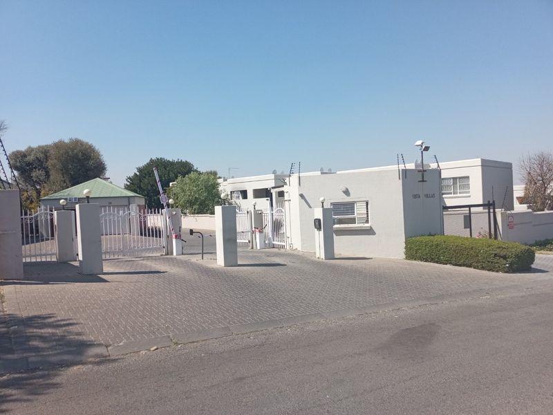 The entrance to Vista Villas featuring a secure gated access point, paved driveway, and perimeter electric fencing.