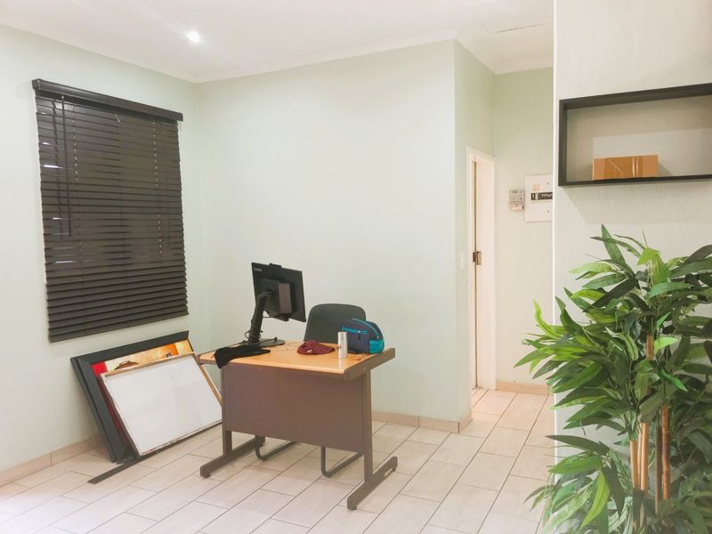 A functional office space featuring tiled flooring, recessed lighting, and a built-in wall shelf, providing a clean and versatile work environment.