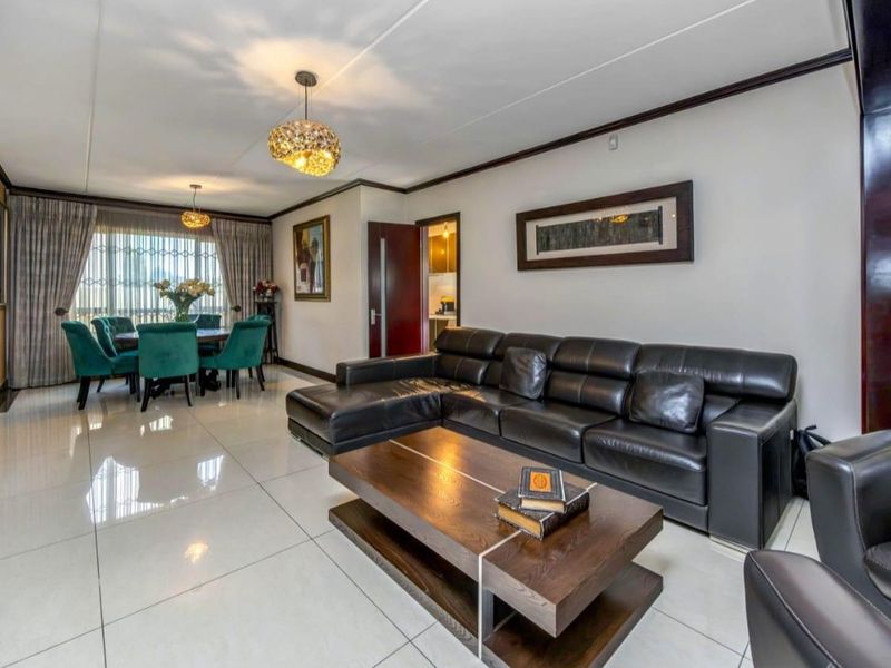 Spacious open-plan living and dining area featuring polished porcelain floor tiles, modern lighting, and direct access to an outdoor space.