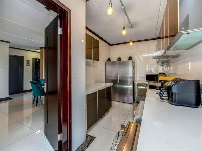 Modern kitchen featuring sleek cabinetry, stone countertops, tiled flooring, and integrated lighting, offering a clean and functional workspace.