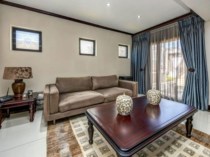 A well-maintained living room featuring tiled flooring, recessed downlighting, and a sliding glass door providing access to the exterior.