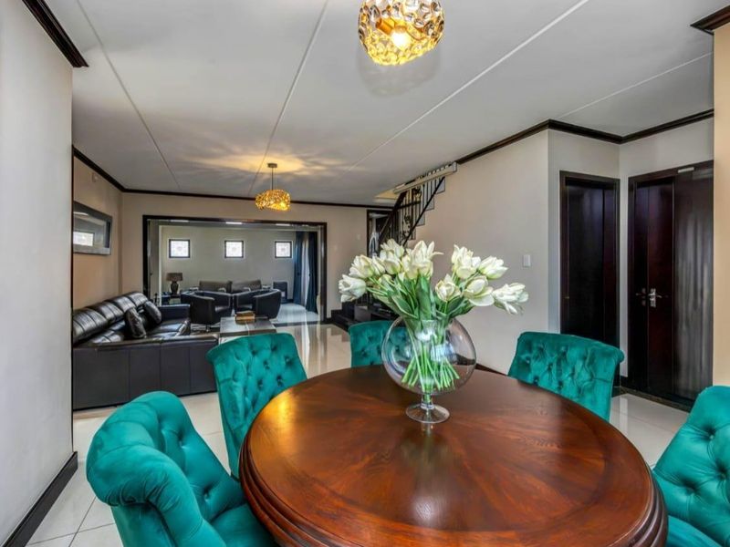 An open-plan living and dining area featuring tiled floors, crown molding, and a staircase leading to the upper level.
