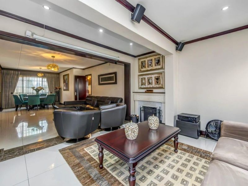 Spacious open-plan living and dining area featuring tiled flooring, recessed lighting, and a classic fireplace, creating a comfortable and connected living space.