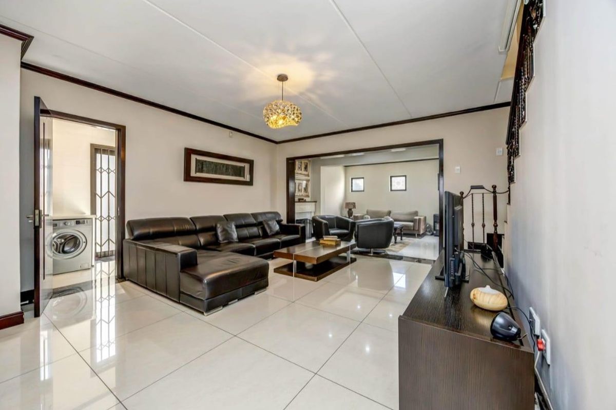 Spacious living area featuring large format floor tiles, neutral walls, and an open-plan layout connecting to an adjacent lounge space.
