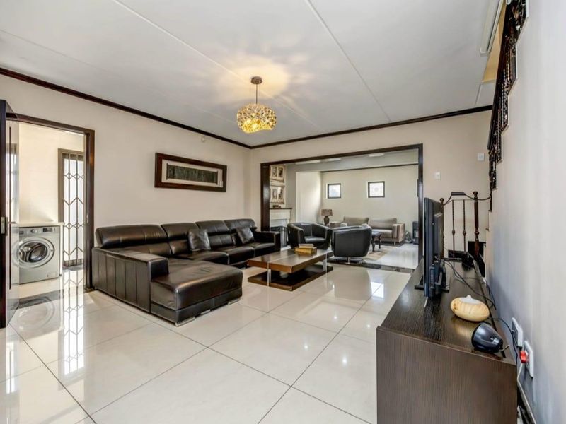 Spacious living area featuring large format floor tiles, neutral walls, and an open-plan layout connecting to an adjacent lounge space.