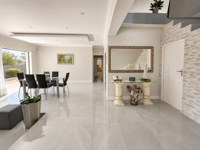 Spacious open-plan living and dining area featuring polished porcelain tiles, modern recessed lighting, and a striking stone-clad feature wall with a contemporary staircase.