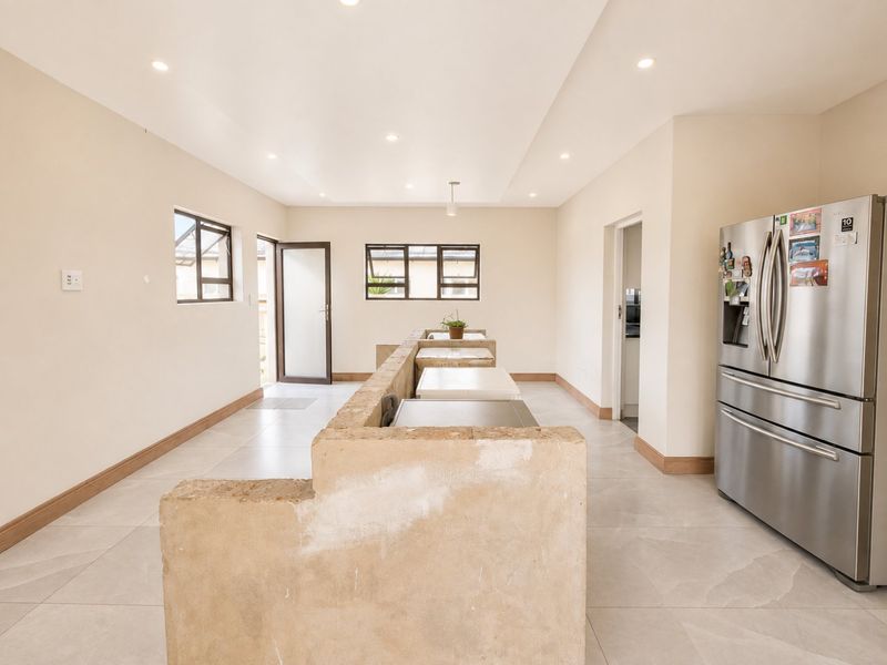 A kitchen area featuring tiled flooring, recessed lighting, and a central masonry island base awaiting final finishes.