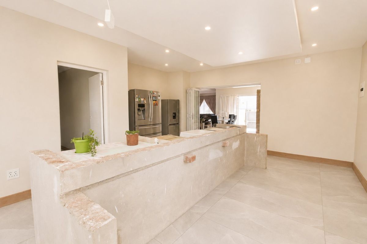Spacious kitchen area featuring large format floor tiles, recessed lighting, and a substantial stone breakfast bar currently in an unfinished state.