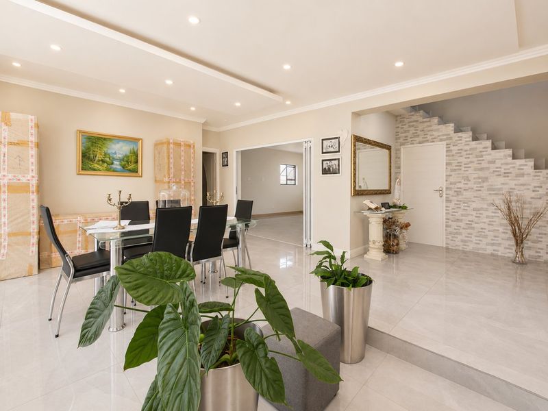 Spacious dining area featuring polished tile flooring, recessed ceiling lighting, and a decorative stone veneer feature wall leading to the staircase.