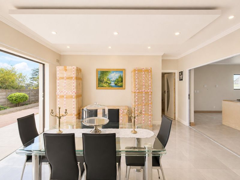 Bright dining room featuring a recessed ceiling with downlights, large sliding glass doors leading to the patio, and polished porcelain floor tiles.