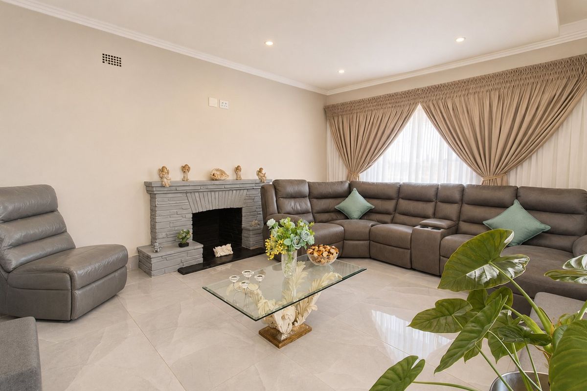 Spacious living room featuring large format floor tiles, a stone fireplace, and recessed downlighting, creating a comfortable and well-maintained living space.