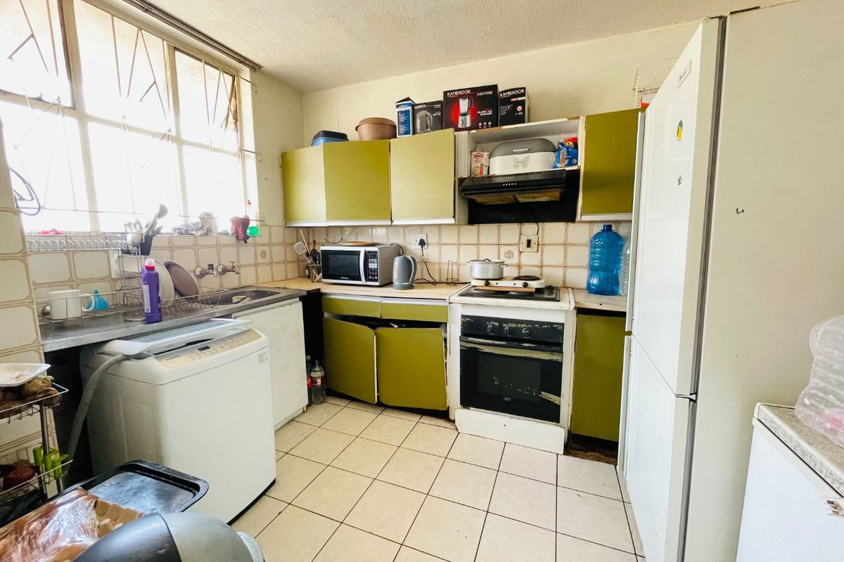 A functional kitchen featuring built-in cabinetry, a tiled backsplash, and integrated cooking appliances, offering potential for modernization and cosmetic updates.