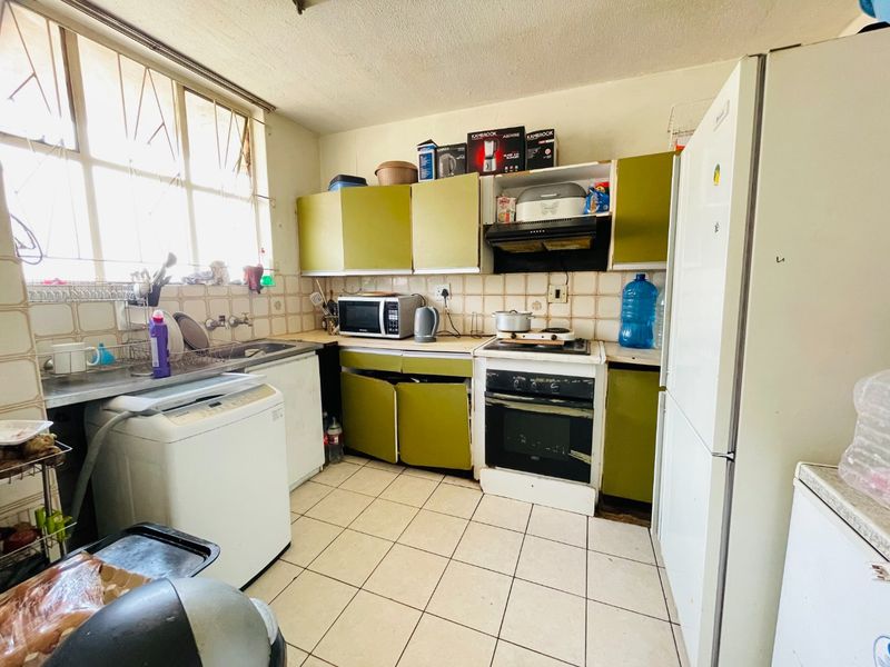 A functional kitchen featuring built-in cabinetry, a tiled backsplash, and integrated cooking appliances, offering potential for modernization and cosmetic updates.