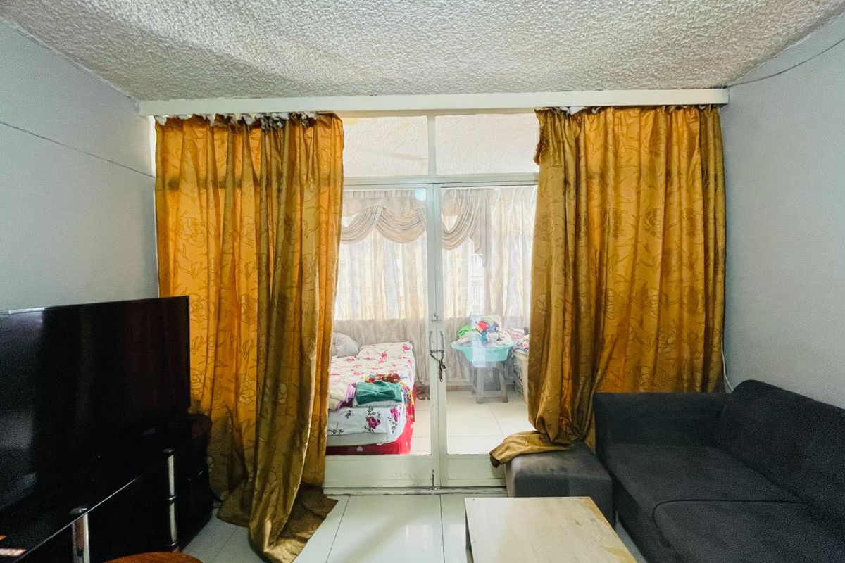 Living room featuring tiled flooring and a sliding glass door leading to an enclosed balcony area with textured ceiling finishes.