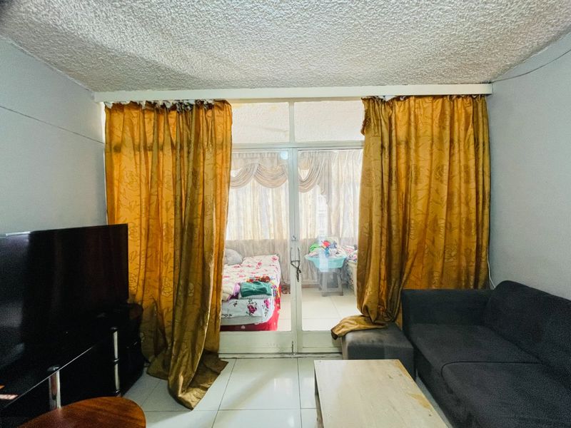 Living room featuring tiled flooring and a sliding glass door leading to an enclosed balcony area with textured ceiling finishes.