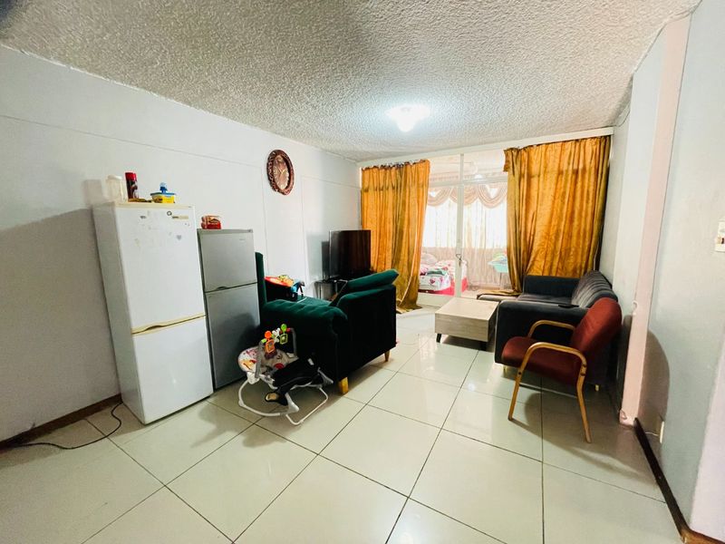 Open plan living area featuring tiled flooring and a sliding glass door leading to an adjacent space, offering a functional layout for daily living.