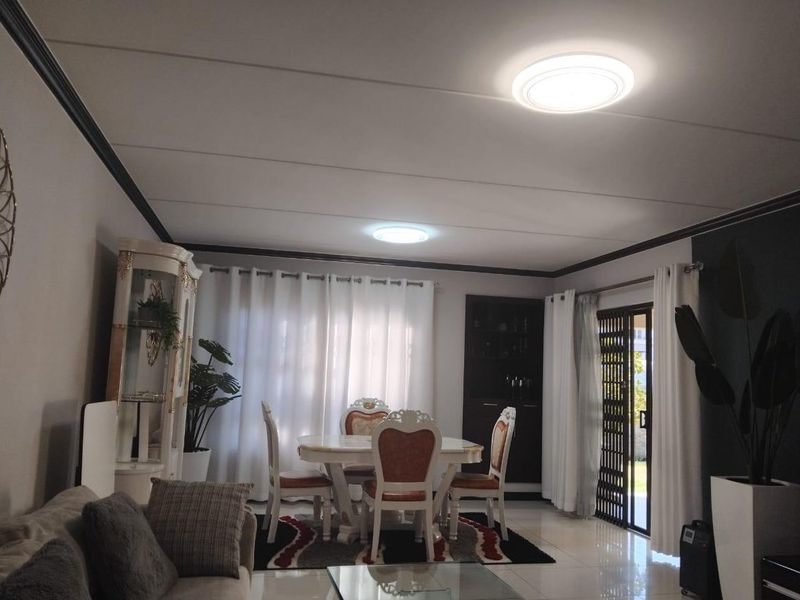 Open-plan living and dining area featuring tiled flooring, recessed ceiling lighting, and a sliding glass door providing access to the exterior.