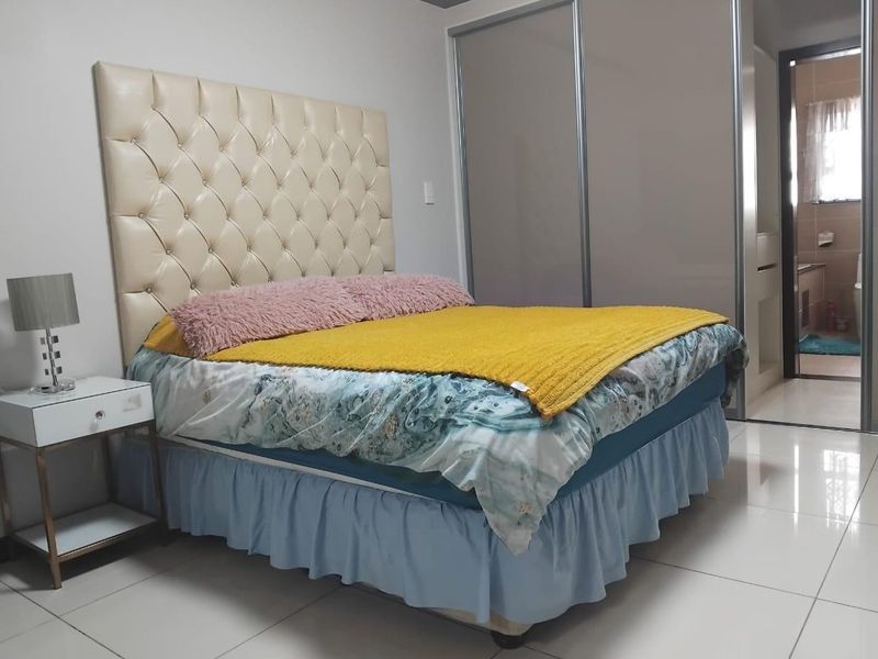 A well-maintained bedroom featuring tiled flooring and a large built-in sliding door wardrobe, with direct access to an en-suite bathroom.