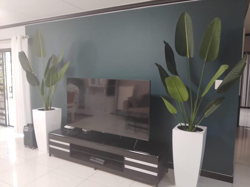 A well-maintained living room featuring a dark teal accent wall and light-colored floor tiles.