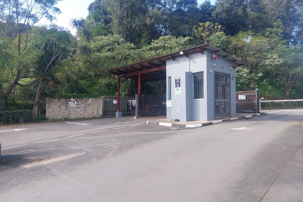 The entrance to Forest Waters estate featuring a security guard house, boom gate access, and stone-clad boundary wall.