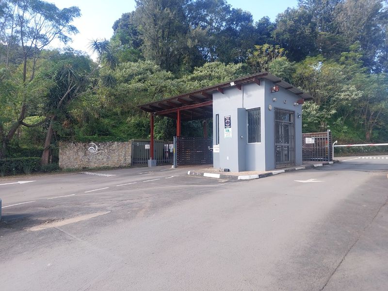 The entrance to Forest Waters estate featuring a security guard house, boom gate access, and stone-clad boundary wall.