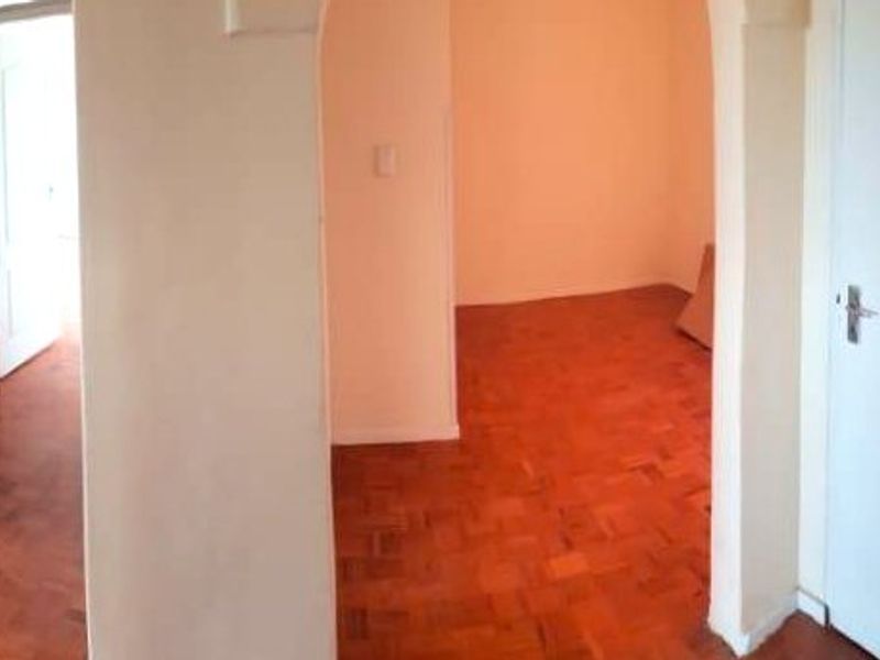 A vacant hallway featuring parquet flooring and arched architectural details, connecting multiple rooms within the apartment.