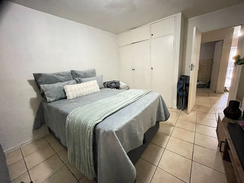 A bedroom featuring tiled flooring and built-in cupboards, offering a functional space with potential for cosmetic updates to enhance its overall appeal.