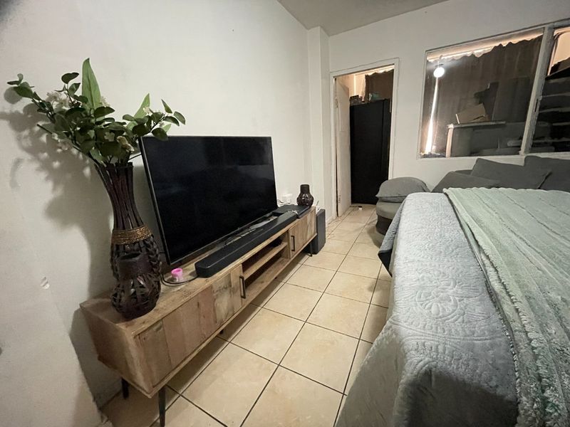 A bedroom featuring tiled flooring and a large window, providing a functional space with potential for cosmetic updates to enhance the interior finish.
