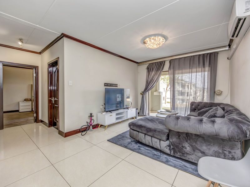 A well-maintained living room featuring large format floor tiles, an integrated air conditioning unit, and direct access to an outdoor balcony area.