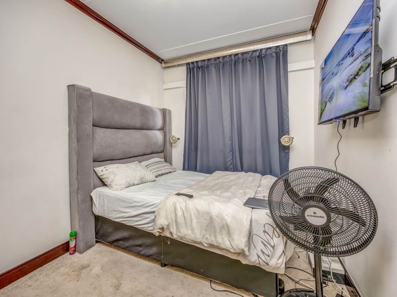 A compact bedroom featuring carpeted flooring, crown molding, and a wall-mounted television bracket.