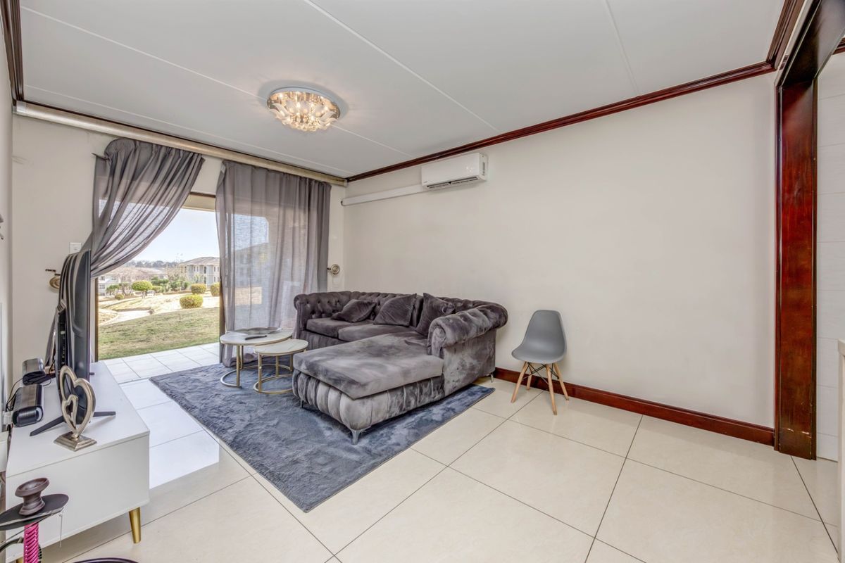 A bright living room featuring large format floor tiles, a split-system air conditioner, and sliding glass doors providing access to the outdoor area.
