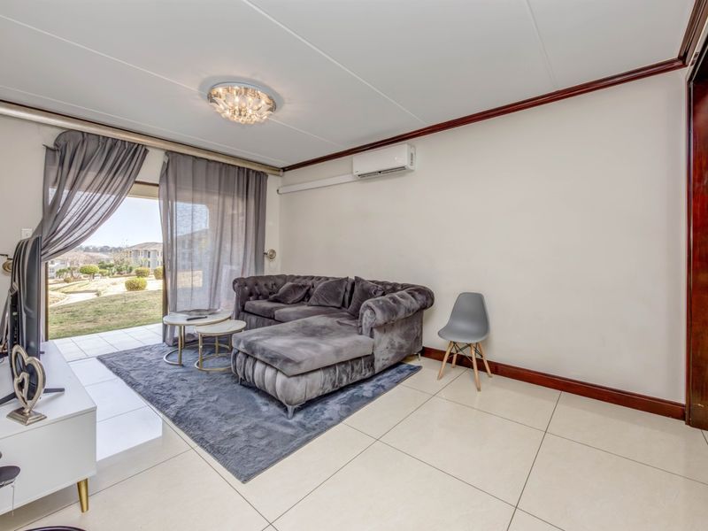 A bright living room featuring large format floor tiles, a split-system air conditioner, and sliding glass doors providing access to the outdoor area.