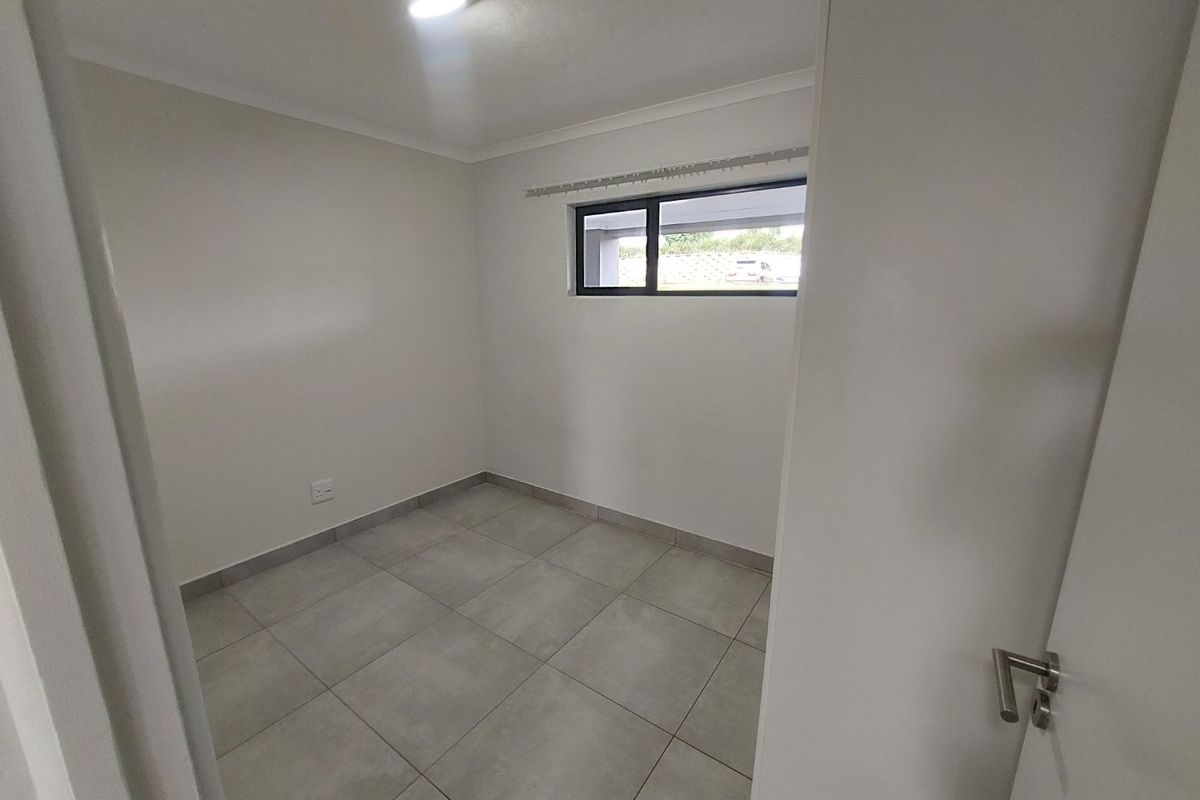 A clean, empty bedroom featuring neutral tiled flooring, white walls, and an aluminium-framed window, providing a blank canvas for personalization.