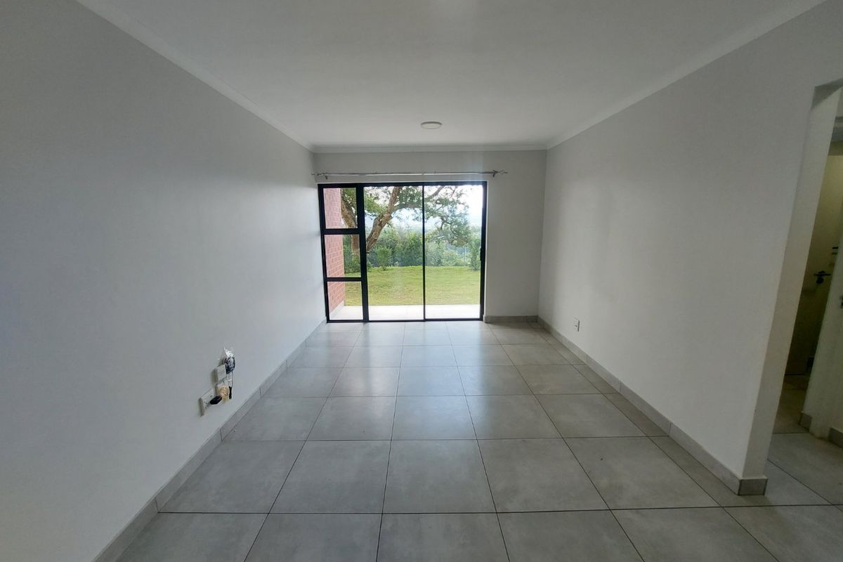 A bright, empty living room featuring large sliding glass doors that provide natural light and access to the outdoor area.