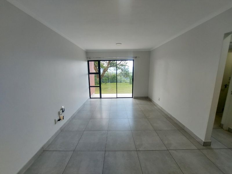 A bright, empty living room featuring large sliding glass doors that provide natural light and access to the outdoor area.