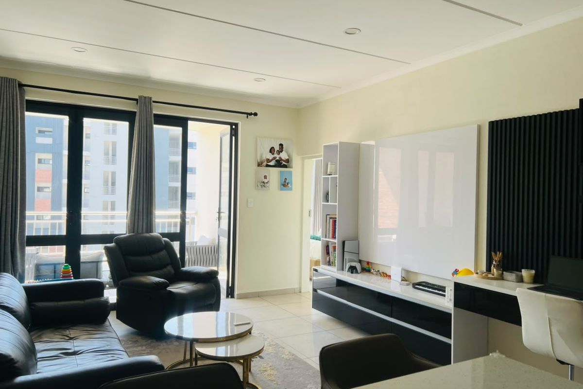 A bright and modern living room featuring tiled floors, recessed lighting, and a sleek built-in media console with integrated slatted wall detailing.