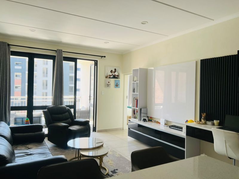 A bright and modern living room featuring tiled floors, recessed lighting, and a sleek built-in media console with integrated slatted wall detailing.