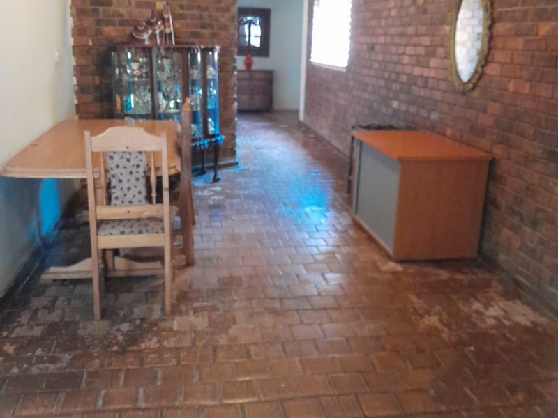 Living area featuring rustic exposed brick walls and traditional terracotta tile flooring, offering a character-filled space with potential for modernization.