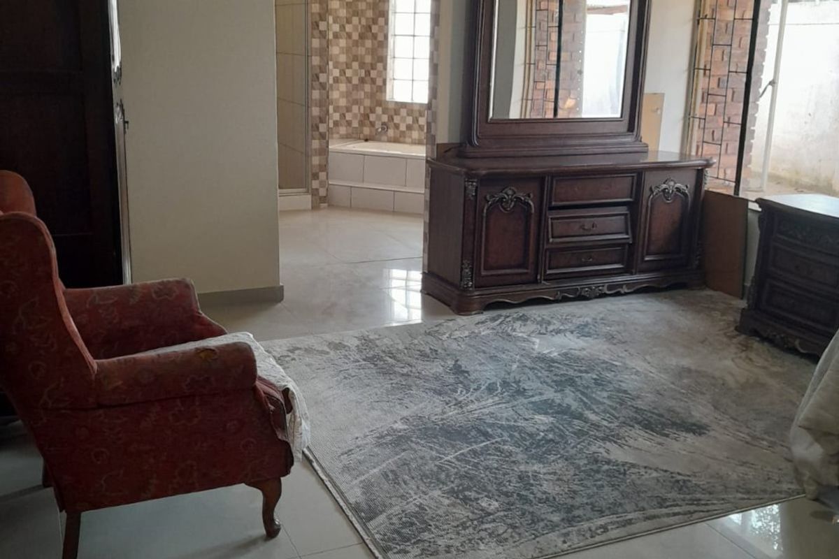 Spacious bedroom featuring tiled flooring and direct access to an en-suite bathroom with a bathtub.
