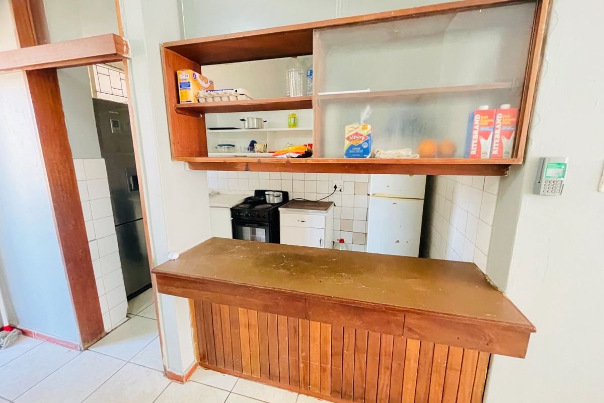 A dated kitchen featuring wooden cabinetry, a breakfast counter, and tiled splashbacks, offering potential for a modern renovation.