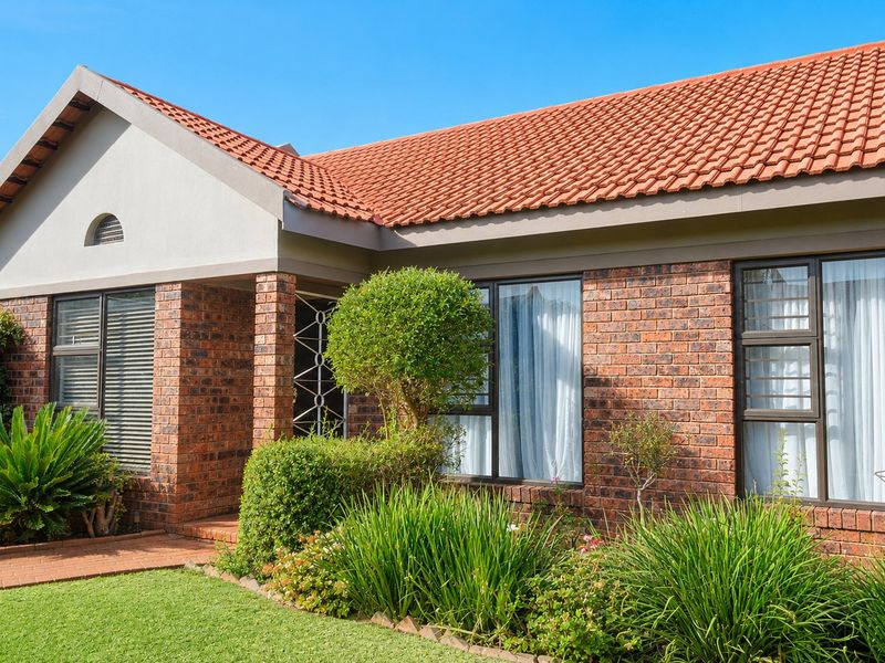 A well-maintained townhouse exterior featuring classic face brick construction, terracotta roof tiles, and established garden landscaping with a paved entrance path.