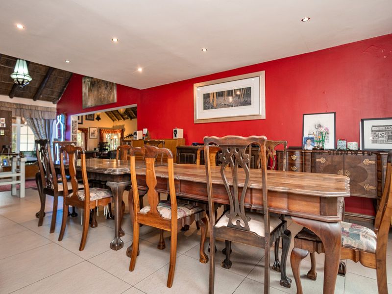 Spacious dining area featuring tiled flooring, recessed downlighting, and a distinctive thatched roof section, providing a unique architectural character.
