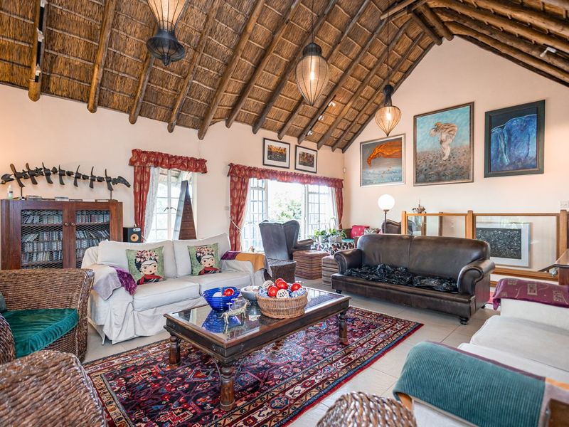 Spacious living room featuring a high vaulted thatched ceiling with exposed timber rafters and tiled flooring.