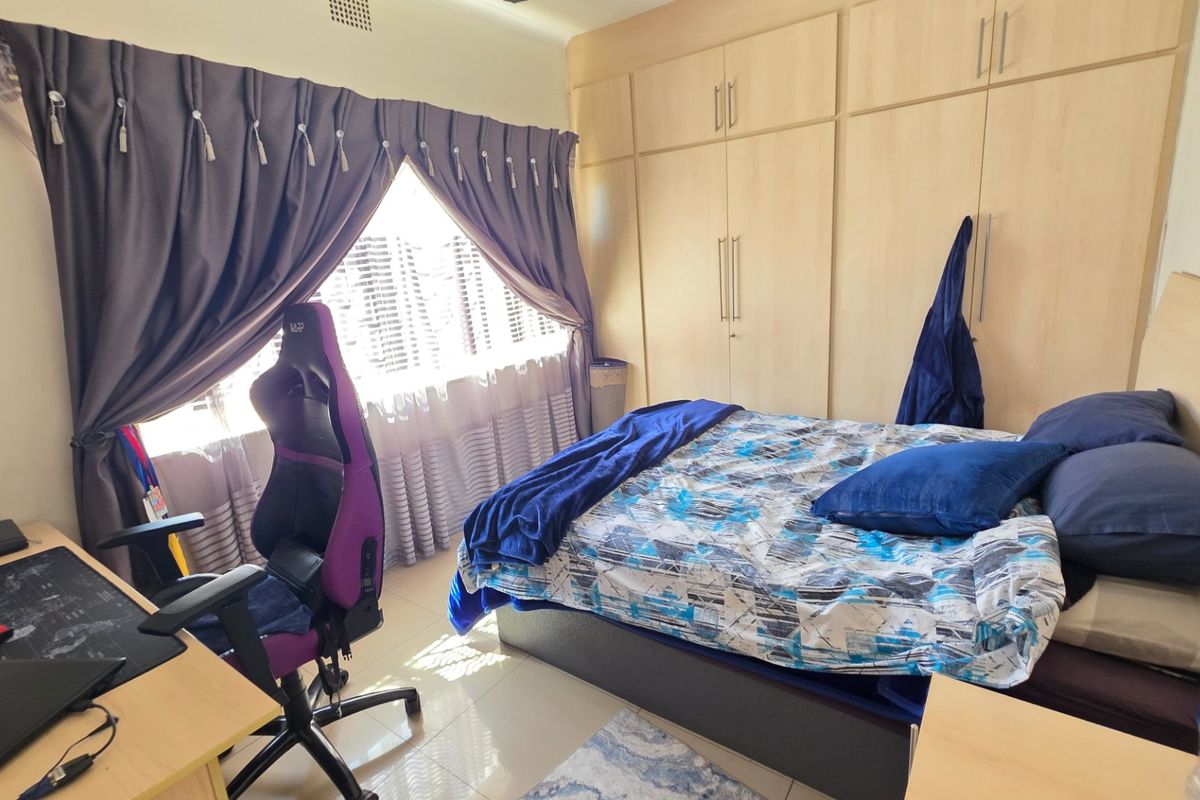 A functional bedroom featuring light wood-finish built-in cupboards and tiled flooring, providing ample storage and a clean, neutral base.