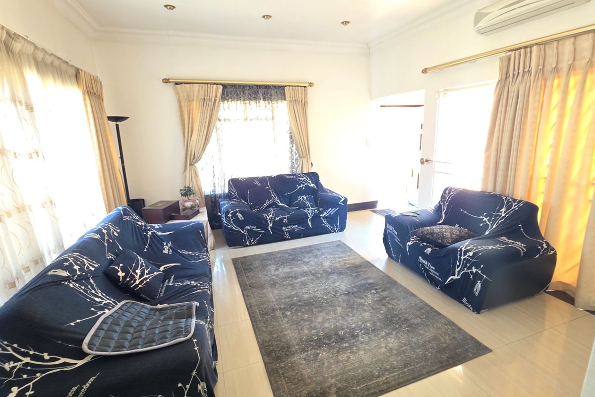 A bright living room featuring tiled flooring, recessed downlighting, and a wall-mounted split-system air conditioner.