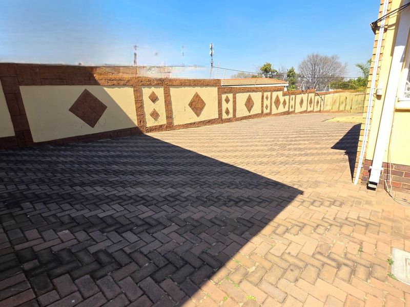 A spacious paved rear courtyard area featuring a decorative perimeter boundary wall and secure exterior access.