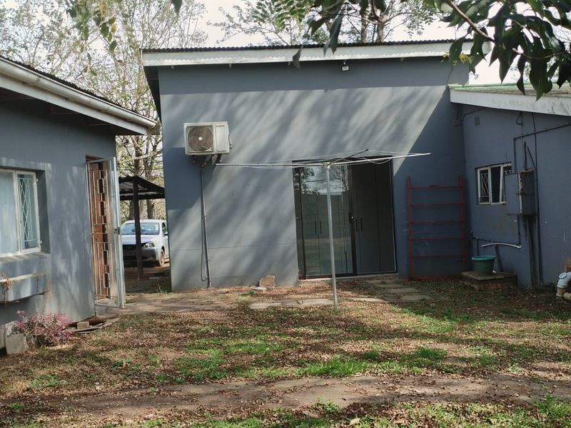 Rear view of the property featuring a paved courtyard area, exterior sink, and sliding door access to the main dwelling.